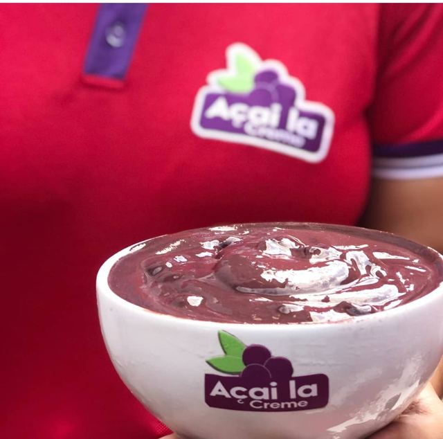 Tigela de açaí grosso servida por atendente com uniforme da Açaí la Creme